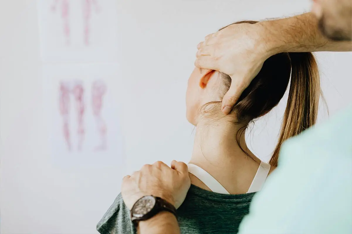 Person med stel nacke och nackspärr som håller handen mot nacken